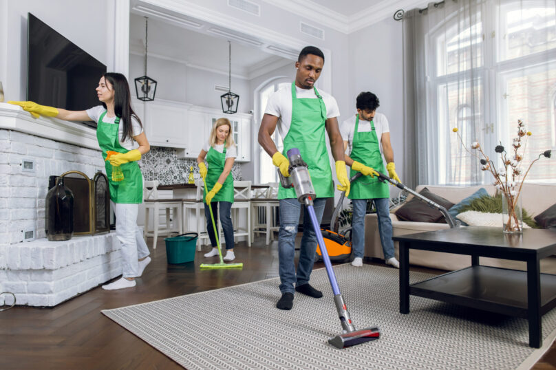 Team of diverse professional hardworking mixed race cleaners from cleaning service, working together in modern luxury house, using cleaning tools. Service industries concept.